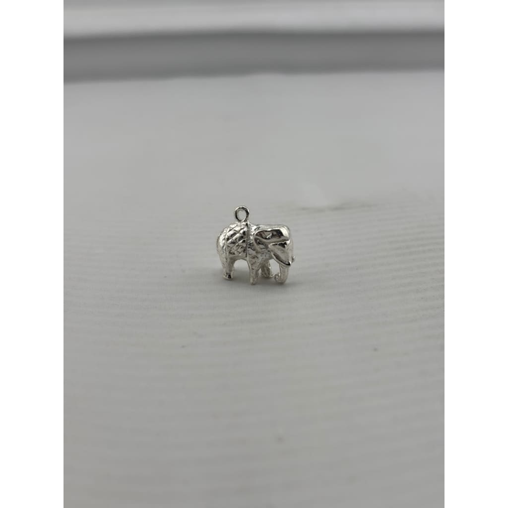 Original three-quarter view of a silver standing elephant pendant with curled trunk